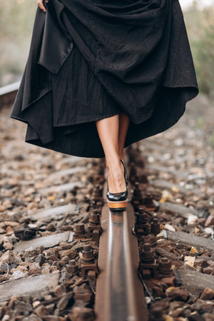 Elegant Woman in Black Dress on Railroad Trackの写真素材