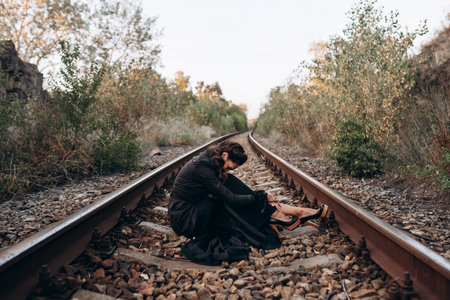 Woman Sitting Alone on Train Tracks in Natureの写真素材
