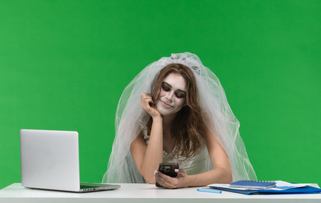 Bride in Ghost Costume Working on Laptop at Deskの写真素材