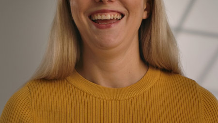 A close up shot of a woman smiling with a visible vibrant smile, wearing a yellow sweater.の写真素材