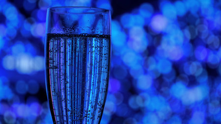 Close up of a champagne glass with sparkling bubbles on a blue bokeh background. Festive mood for holiday, New Years, and Christmas parties.の写真素材