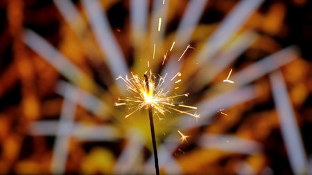Close up of Bengal fire burning with bright golden sparks against the backdrop of bokeh fireworks....