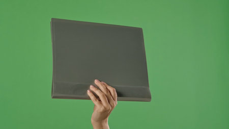 A woman hand holding a gray office folder with documents on a green chroma key background. Shot for designs related to office, business, education, and training.の写真素材