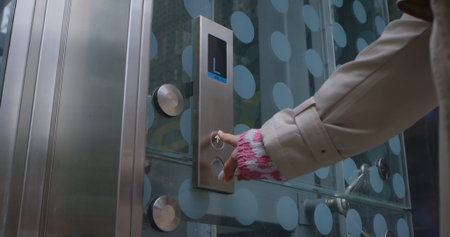 Close up of a person pressing an elevator button on a glass door panel with metal elements.