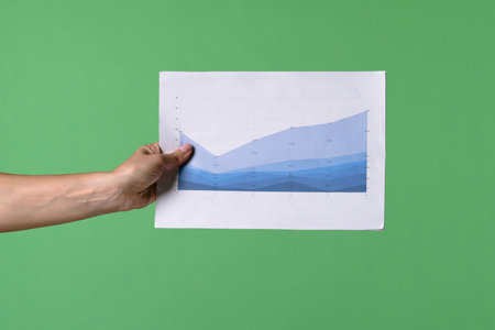 A woman hand holding a economic graphs on a green chroma key background. Shot for designs related to office, business, startup, economy, and stock market.の写真素材