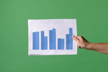 A woman hand holding a economic graphs on a green chroma key background. Shot for designs related to office, business, startup, economy, and stock market.の写真素材