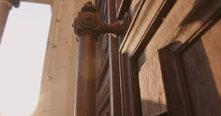 A detailed view of an antique wooden door with intricate carvings and a decorative handle,...
