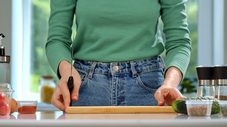 A woman in casual clothes prepares breakfast in a bright, cozy home kitchen, using fresh ingredients.の写真素材