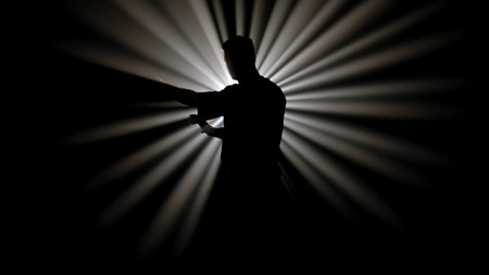 A dark figure of a martial arts master practices his skills, performing various stances in front of a powerful white light, creating radial rays of illumination.の写真素材