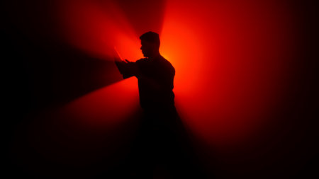 A dark figure of a martial arts master practices his skills, performing various stances in front of a powerful red light, creating dramatic rays of illumination.の写真素材
