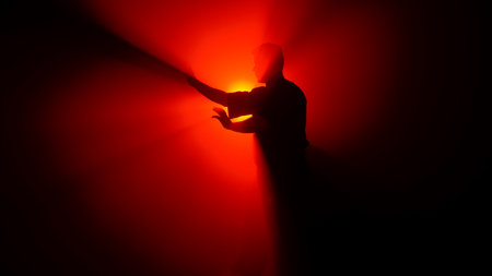 A dark figure of a martial arts master practices his skills, performing various stances in front of a powerful red light, creating dramatic rays of illumination.の写真素材