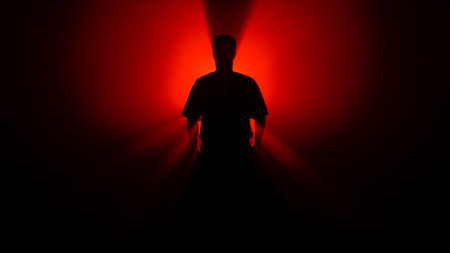 A dark figure of a martial arts master practices his skills, performing various stances in front of a powerful red light, creating dramatic rays of illumination.の写真素材