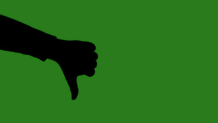 A black isolated silhouette of a man hand shows a finger thumb down close up on a green chroma key background. Minimalist contrast and modern visual composition, mockup.の写真素材