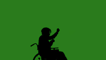 A black silhouette of a man in a wheelchair dancing while seated, against a green chroma key background. Minimalist contrast and modern visual composition, mockup.の写真素材