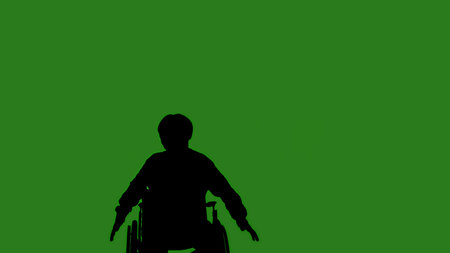 A black silhouette of a man in a wheelchair dancing while seated, against a green chroma key background. Minimalist contrast and modern visual composition, mockup.の写真素材