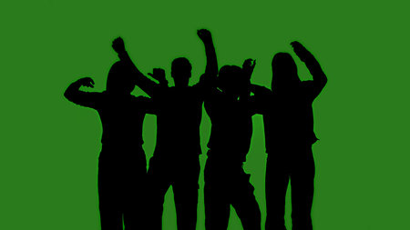 Black isolated silhouettes of people dancing cheerfully on a green chroma key background. Minimalist contrast and modern visual composition, mockup.の写真素材