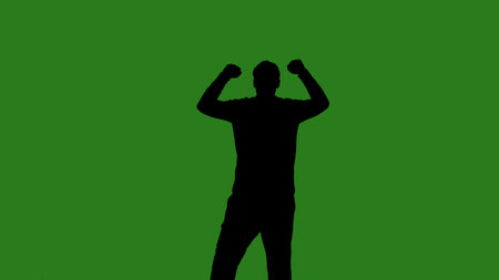 A black silhouette of a man dances against a green chroma key background. Minimalist contrast and...