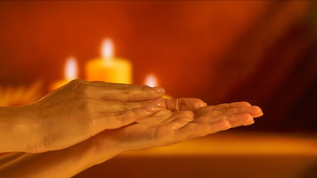A close up of hands applying cream with soothing candlelight in the background creating a warm ambiance. Beauty concept, skin care, and cream product presentation.の写真素材