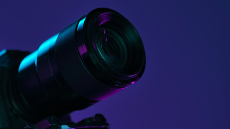 A detailed view of a camera lens illuminated by vibrant neon lighting, set against a dark background.の写真素材