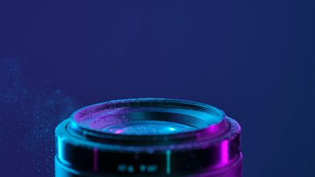 Macro shot of a camera lens with blue neon light and a cloud of fine dust creating an artistic...
