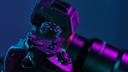 Detailed view of a camera under vibrant neon lighting, showcasing buttons and dials with artistic effect.の写真素材