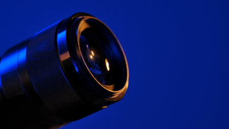 Detailed close up of a camera lens against a blue background, highlighting the intricate design and craftsmanship.の写真素材