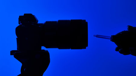 A silhouette of a camera lens and lens blower against a vivid blue background, emphasizing photography equipment.の写真素材