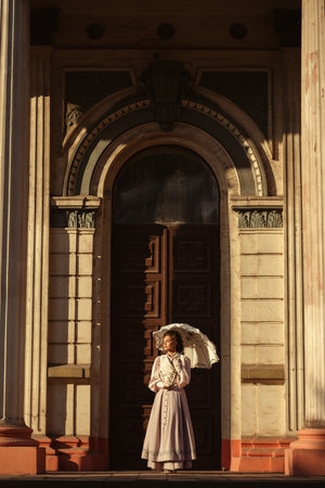 An elegant woman in a vintage dress holds a lace parasol under the warm rays of the sun.