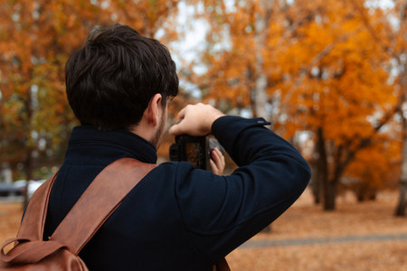 Photographer Capturing Autumn Scene with Cameraの写真素材