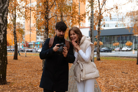 Happy Couple Reviewing Photos in Autumn Parkの写真素材