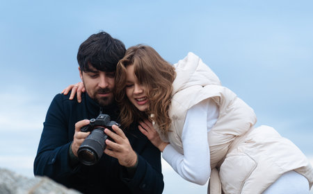 A couple looks at photos taken with a digital camera outdoors.