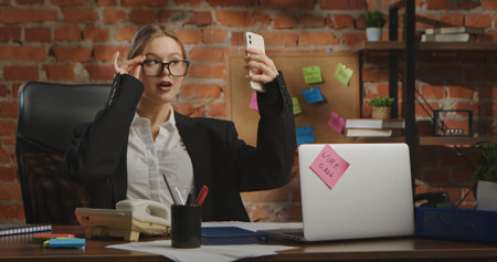 Confident Businesswoman Taking a Fun Selfie at Her Deskの写真素材