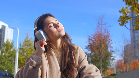 Woman Relaxing with Headphones in Urban Autumn Settingの写真素材