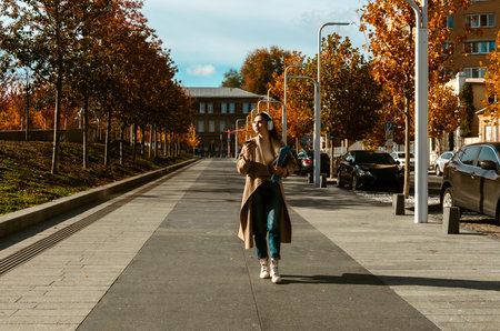 Woman Walking with Headphones and Coffee in Autumn City