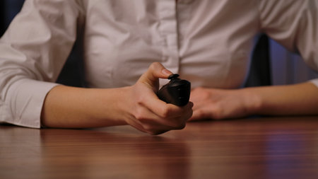 Close up of a woman in a white business shirt interacting with a wireless remote controlの写真素材