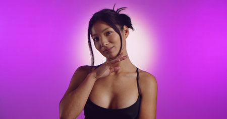 A young Korean model poses in a studio lit by pink neon lightsの写真素材