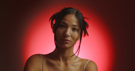 Portrait of a young Korean model in a red circle of light from a spotlight.