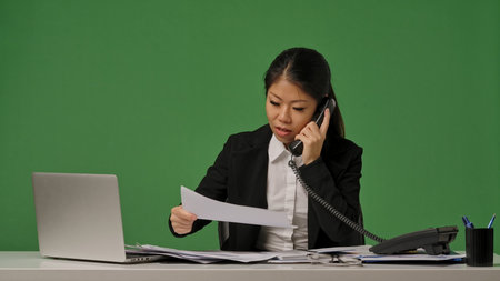 A young Korean businesswoman in a black suit is talking on the phoneの写真素材