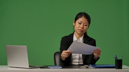 A young Korean businesswoman in a black suit looks through documents with graphsの写真素材