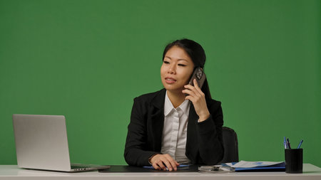 A young Korean businesswoman in a black suit is talking on the smartphone