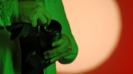 Photographer Cleaning Camera Lens with Cloth in Green Lightの写真素材