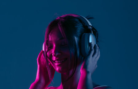 Woman Enjoying Music in Headphones with Neon Lightingの写真素材