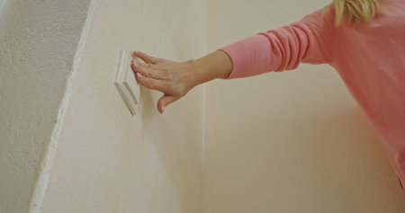 Woman Turning Off Light Switch on Wall