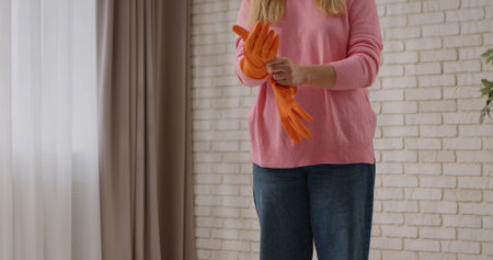 Woman in Pink Sweater Putting on Orange Cleaning Gloves