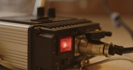 Close up of active lighting controller with glowing red switch and connected power cable, warm lighting sceneの写真素材