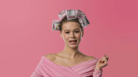 A woman in a pink blouse, with curlers in the form of banknotes in her hair against a pink...