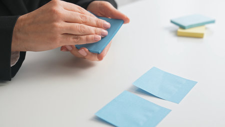 A person arranging blue sticky notes on a white desk, emphasizing organization and planning in a...