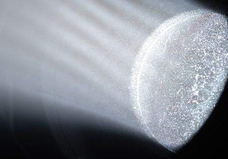 Close up of dust particles illuminated by a strong spotlight beam, revealing light rays and circular...
