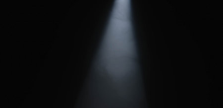 A powerful, focused beam of white light emanating from a spotlight in a dark room creates striking...