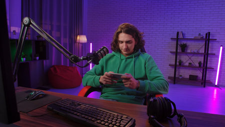 Daily lifestyle concept. Young adult man spending time at home, man streamer gamer sits at desk with...